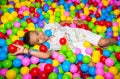 Happy african black boy playing in ball pit on birthday party in kids amusement park and indoor play center. Child Royalty Free Stock Photo