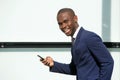 Happy african businessman walking in city with mobile phone Royalty Free Stock Photo