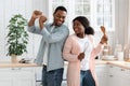 Happy african couple having fun in kitchen, dancing with utencils in hands Royalty Free Stock Photo