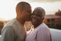 Happy african couple having tender moment outdoors at summer sunset - Focus on woman face