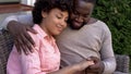Happy african couple hugging on bench, outdoor date in city cafe, closeness Royalty Free Stock Photo