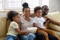 Happy african couple with kids relaxing at home watching tv Royalty Free Stock Photo