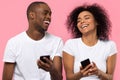 Happy african couple laughing using smartphones isolated on pink background Royalty Free Stock Photo