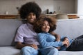 Happy African couple resting on couch, hugging, looking at camera Royalty Free Stock Photo