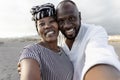 Happy African couple taking selfie on the beach with mobile smartphone camera during summer vacation Royalty Free Stock Photo