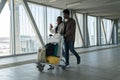 Happy African couple travel after coronavirus pandemic end. Black passengers in airport with luggage