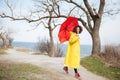 Happy african curly young lady wearing yellow coat holding umbrella