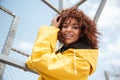 Happy african curly young lady wearing yellow coat