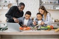 Happy african cute little sons and their young parents having online cooking class on laptop Royalty Free Stock Photo