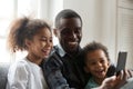 Happy african dad laughing using smartphone with kids at home Royalty Free Stock Photo