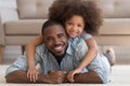 Happy african dad lying on floor carrying daughter, portrait Royalty Free Stock Photo