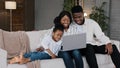 Happy African family and cute kid child girl daughter using laptop looking at computer screen enjoying watching funny Royalty Free Stock Photo