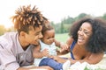 Happy African family enjoying a picnic sunny day outdoor - Mother and father having fun with their daughter in a public park Royalty Free Stock Photo