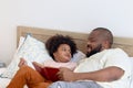 Happy African family, father and son spending time together, young boy with black curly hair and dad reading a book together while Royalty Free Stock Photo