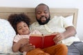 Happy African family, father and son spending time together, young boy with black curly hair and dad reading a book together while Royalty Free Stock Photo