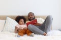 Happy African family, father and son spending time together, young boy with black curly hair and dad reading a book together while Royalty Free Stock Photo