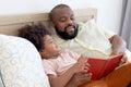 Happy African family, father and son spending time together, young boy with black curly hair and dad reading a book together while Royalty Free Stock Photo