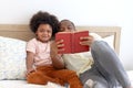 Happy African family, father and son spending time together, young boy with black curly hair and dad reading a book together while Royalty Free Stock Photo