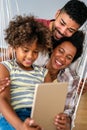 Happy african family having fun with device at home, black parents and child using digital tablet Royalty Free Stock Photo