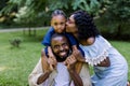 Happy African family with kid girl on a picnic in park. Smiling handsome father holds his cute daughter on the shoulders Royalty Free Stock Photo