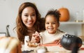 Happy african family mother and cute little girl painting Halloween pumpkins together at home Royalty Free Stock Photo