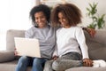 Happy african family mother and daughter use laptop on couch Royalty Free Stock Photo