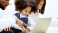 Happy african family parents and little children enjoy using computer laptop together sit on sofa Royalty Free Stock Photo