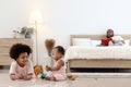 Happy African family spending time together, brother boy with black curly hair lying on floor, playing toy with little cute toddle Royalty Free Stock Photo