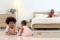 Happy African family spending time together, brother boy with black curly hair lying on floor, playing toy with little cute toddle Royalty Free Stock Photo