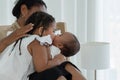 Happy African family, young mother and daughters, little kid older sister tender kissing her newborn baby sister hand Royalty Free Stock Photo