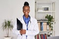 Happy african female doctor looking at camera standing holding clipboard. Royalty Free Stock Photo