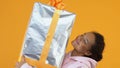 Happy african female holding sizable gift box in hands, holiday package, sale