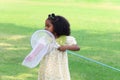 Happy African girl with black curly hair holds scoop-net for catching insect bug and butterfly in green garden. Child explores Royalty Free Stock Photo