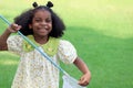 Happy African girl with black curly hair holds scoop-net for catching insect bug and butterfly in green garden. Child explores Royalty Free Stock Photo