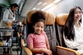 Happy African girl child, kid passenger sitting in comfortable seat inside airplane during female air hostess pushing cart on Royalty Free Stock Photo