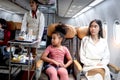 Happy African girl child and woman passenger sit in comfortable seat inside airplane during female air hostess pushing cart on Royalty Free Stock Photo