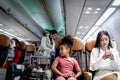 Happy African girl child and woman passenger sit in comfortable seat inside airplane during female air hostess pushing cart on Royalty Free Stock Photo