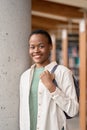 Happy African girl student holding backpack in library, vertical portrait. Royalty Free Stock Photo