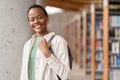 Happy African girl student holding backpack standing in library, portrait. Royalty Free Stock Photo