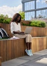 Happy African girl student studying online using laptop sitting outside campus. Royalty Free Stock Photo