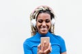 Happy african girl watching videos and listening music with mobile phone app - Young person having fun with new technology trends Royalty Free Stock Photo