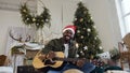 Happy african guy with guitar and bengal light sittingon the floor in a glittering golden confetti on the background of