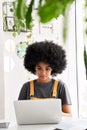 Happy African lady student using laptop sitting at table at home, in cafe. Royalty Free Stock Photo