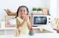 Happy African little child girl smiling and clapping hands after finished playing wooden blocks toy and pyramid puzzle in kitchen Royalty Free Stock Photo