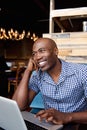 Happy african man sitting at a cafe with laptop Royalty Free Stock Photo