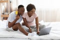 Happy african man and woman with laptop and credit card