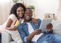 Happy african man and woman shopping online, using digital tablet Royalty Free Stock Photo