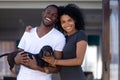 Happy african millennial couple embrace outdoors holding pet, portrait Royalty Free Stock Photo