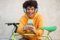 Happy african millennial guy listening music playlist with smartphone app outdoor - Young man having fun with technology trends - Royalty Free Stock Photo