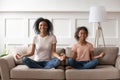 Happy african mom teaching kid daughter doing yoga at home